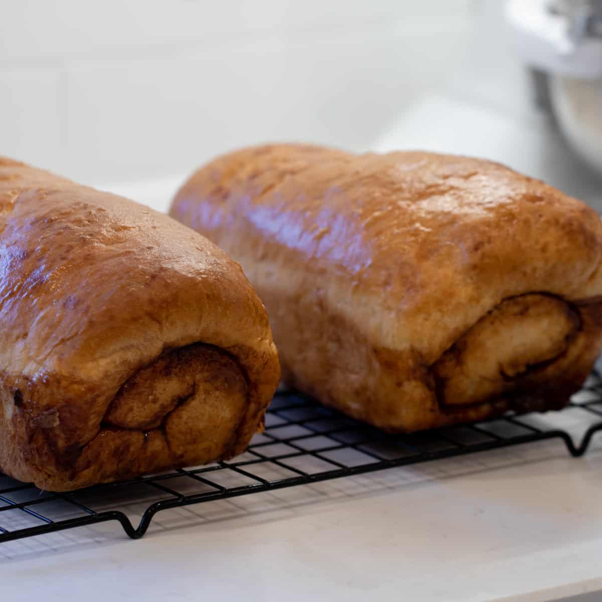 Two love of bread on a cooling rack.