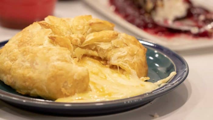 Delicious appetizer recipe of baked brie cheese wrapped in puff pastry with apricot jam and walnuts.