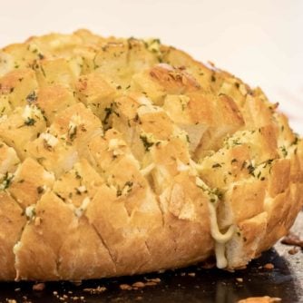 Cheesy pull apart bread made with an artisan rustic round bread loaf, sliced and filled with grated mozzarella cheese, minced garlic, melted butter and parsley. Baked until cheese is bubbly!