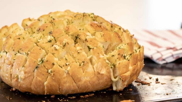 Cheesy pull apart bread made with an artisan rustic round bread loaf, sliced and filled with grated mozzarella cheese, minced garlic, melted butter and parsley. Baked until cheese is bubbly!