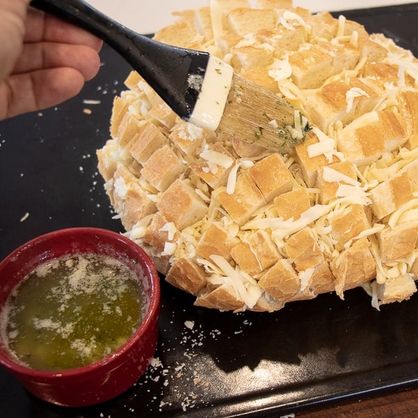 Cheesy pull apart bread made with an artisan rustic round bread loaf, sliced and filled with grated mozzarella cheese, minced garlic, melted butter and parsley. Baked until cheese is bubbly!