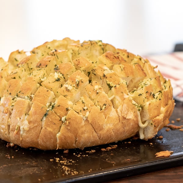 Cheesy pull apart bread made with an artisan rustic round bread loaf, sliced and filled with grated mozzarella cheese, minced garlic, melted butter and parsley. Baked until cheese is bubbly!