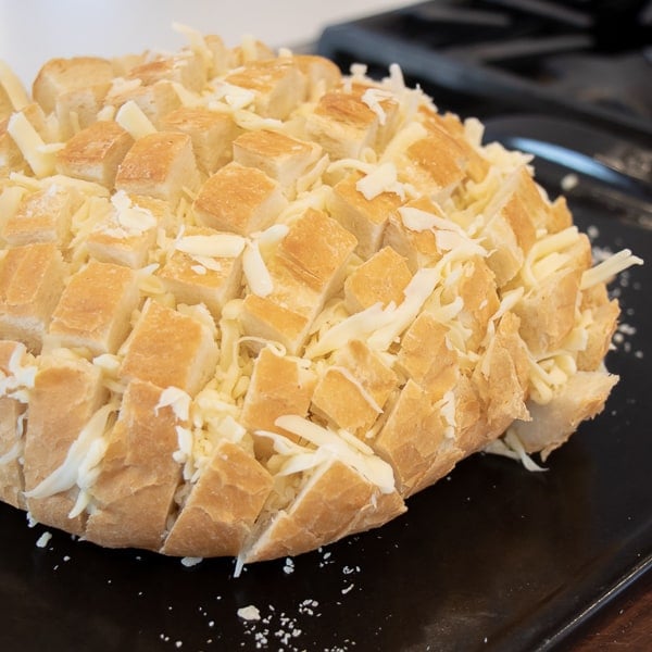 Cheesy pull apart bread made with an artisan rustic round bread loaf, sliced and filled with grated mozzarella cheese, minced garlic, melted butter and parsley. Baked until cheese is bubbly!