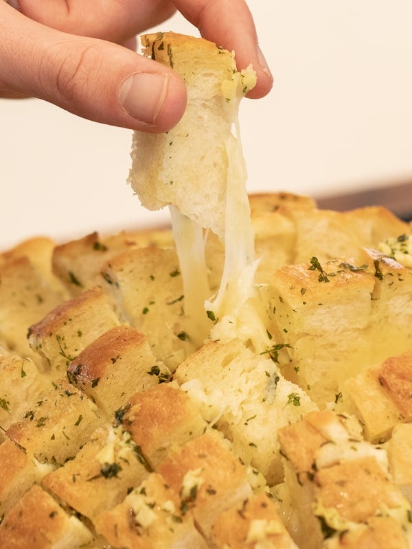 Cheesy pull apart bread made with an artisan rustic round bread loaf, sliced and filled with grated mozzarella cheese, minced garlic, melted butter and parsley. Baked until cheese is bubbly!