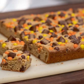 This chewy peanut butter blondie has mini Reese' Pieces, chopped peanut butter cup minis and chocolate chips. A delicious dessert and alternative to a brownie.