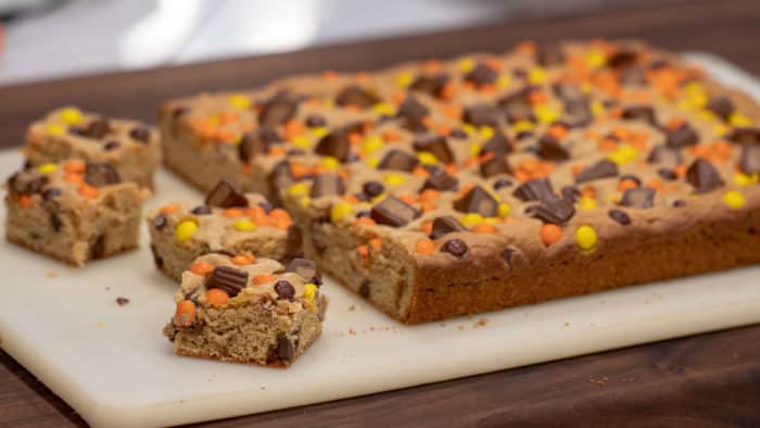 This chewy peanut butter blondie has mini Reese' Pieces, chopped peanut butter cup minis and chocolate chips. A delicious dessert and alternative to a brownie.