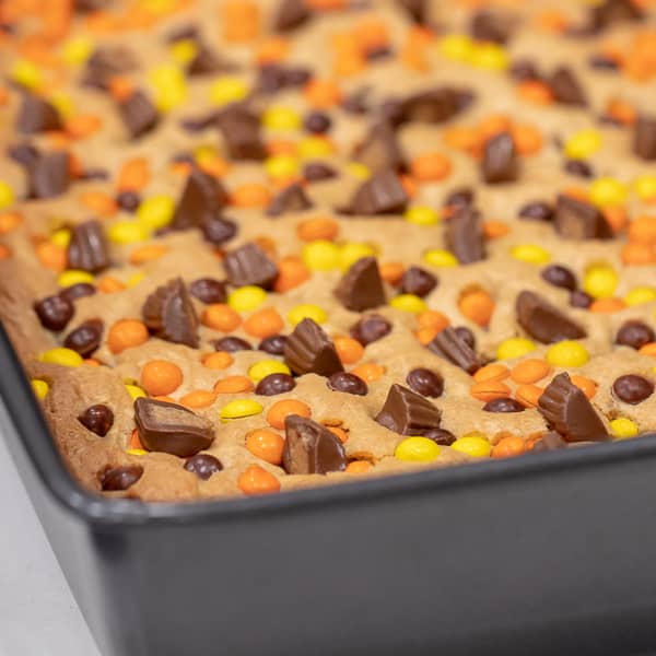 This chewy peanut butter blondie has mini Reese' Pieces, chopped peanut butter cup minis and chocolate chips. A delicious dessert and alternative to a brownie.