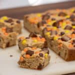 This chewy peanut butter blondie has mini Reese' Pieces, chopped peanut butter cup minis and chocolate chips. A delicious dessert and alternative to a brownie.