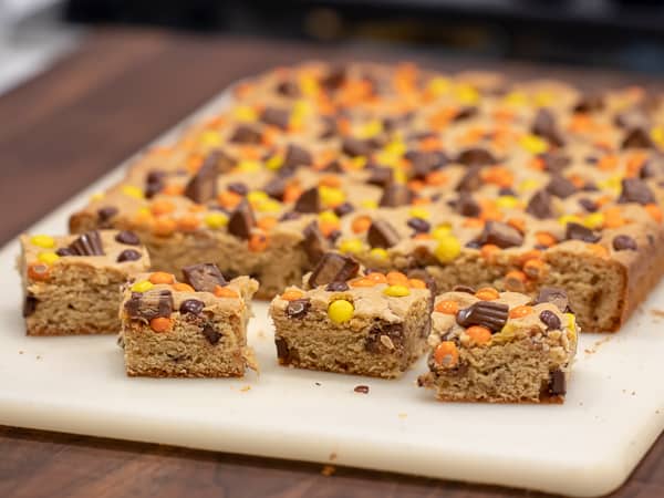 This chewy peanut butter blondie has mini Reese' Pieces, chopped peanut butter cup minis and chocolate chips. A delicious dessert and alternative to a brownie.