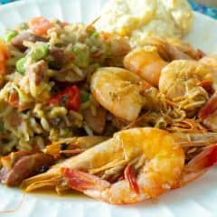 A plate of cooked shrimp with a rice and bean side dish.