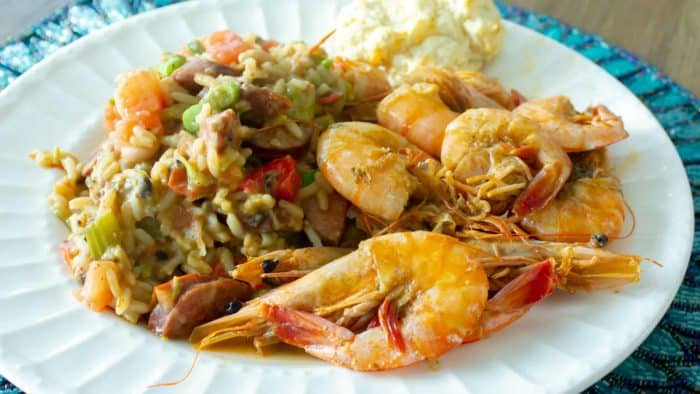 A plate of cooked shrimp with a rice and bean side dish.