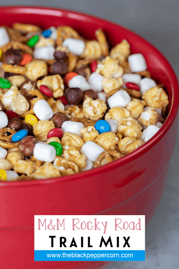 A large red bowl full of caramel popcorn, pretzels, marshmallows and more.