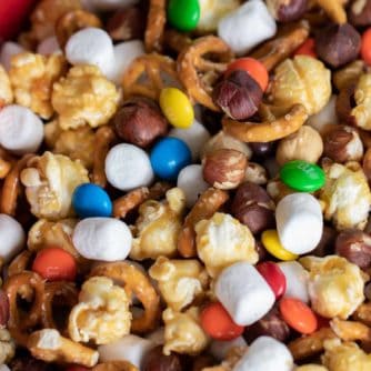 Sweet and salty trail mix recipe made with caramel corn, marshmallows, M&Ms, toasted hazelnuts and mini pretzels. Chocolate, nuts and more, make for a great snack.
