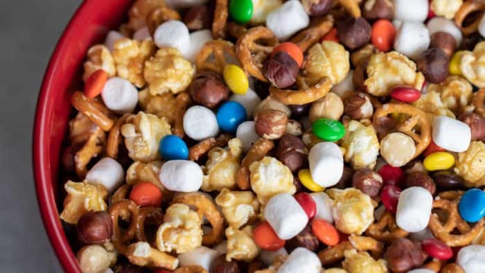 Sweet and salty trail mix recipe made with caramel corn, marshmallows, M&Ms, toasted hazelnuts and mini pretzels. Chocolate, nuts and more, make for a great snack.