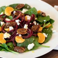 Fresh and healthy salad recipe made with baby spinach, spiralled beets, mandarin oranges, candied pecans and crumbled goat cheese with a honey dijon vinaigrette.