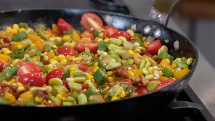 Easy skillet recipe for how to make succotash with lima beans, bacon, corn, okra, grape tomatoes. Classic southern side dish comfort food.