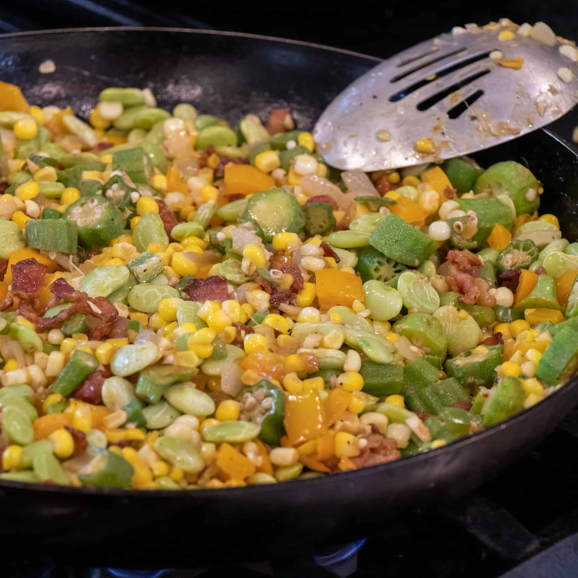 Easy skillet recipe for how to make succotash with lima beans, bacon, corn, okra, grape tomatoes. Classic southern side dish comfort food.