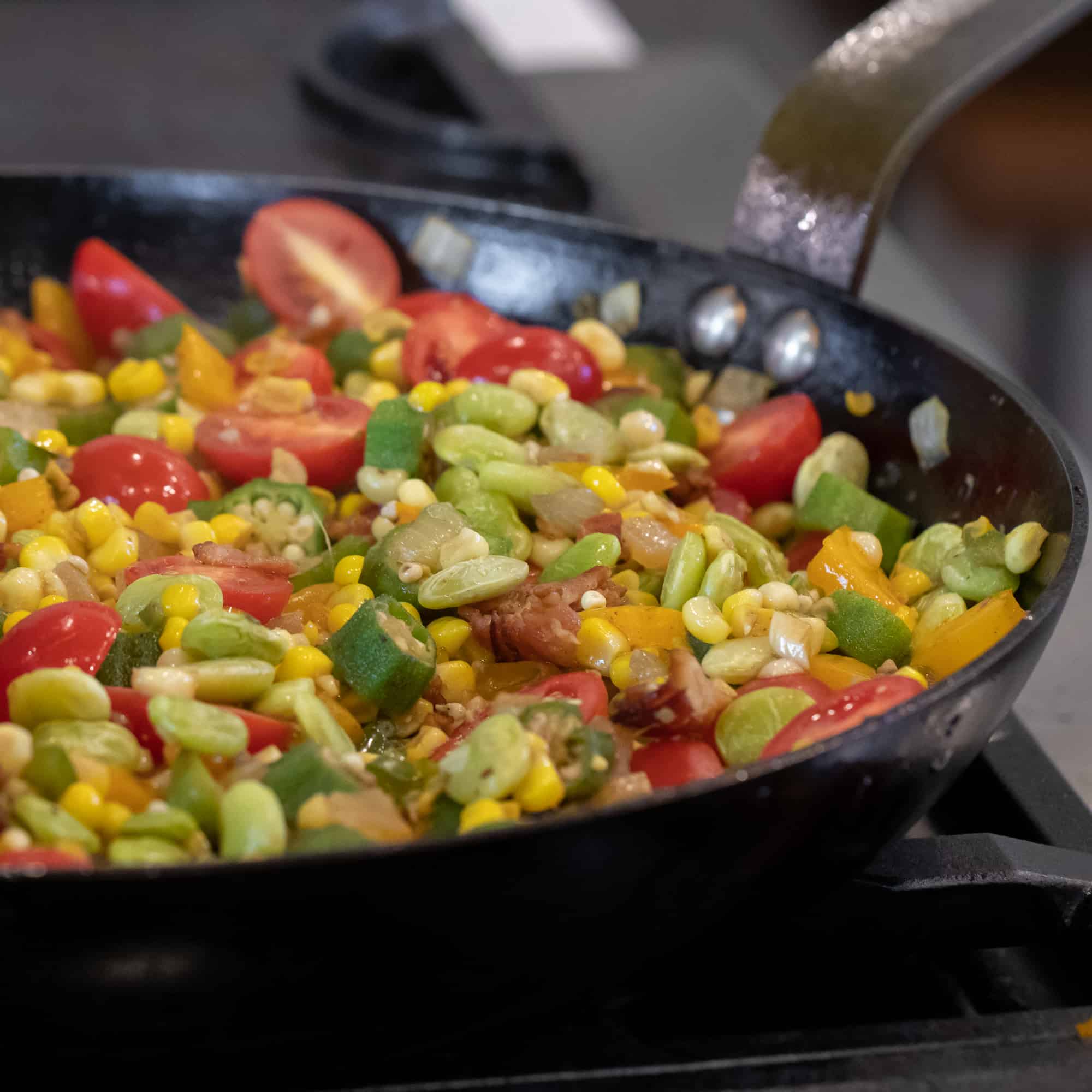 Easy skillet recipe for how to make succotash with lima beans, bacon, corn, okra, grape tomatoes. Classic southern side dish comfort food.