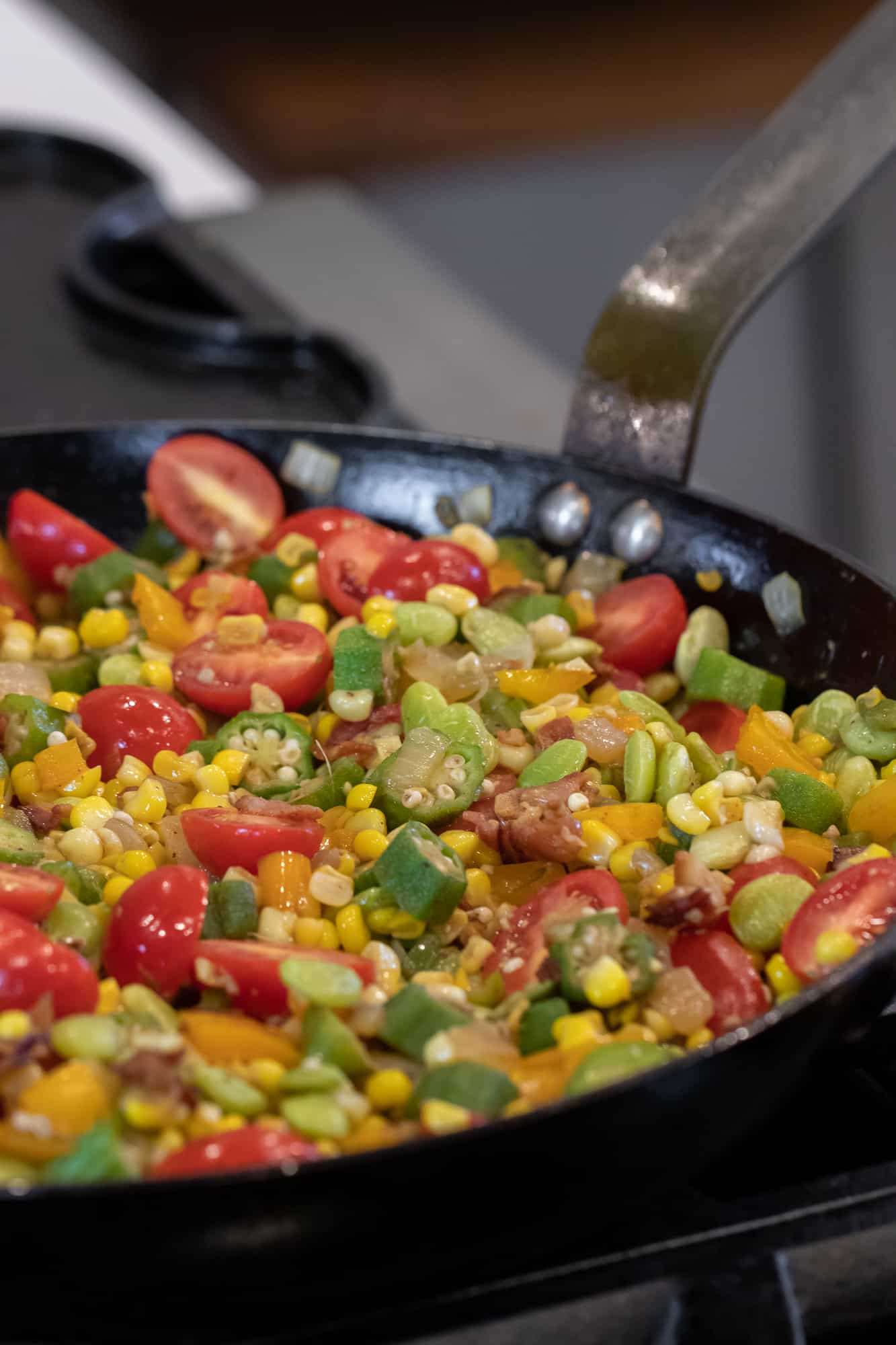 Easy skillet recipe for how to make succotash with lima beans, bacon, corn, okra, grape tomatoes. Classic southern side dish comfort food.