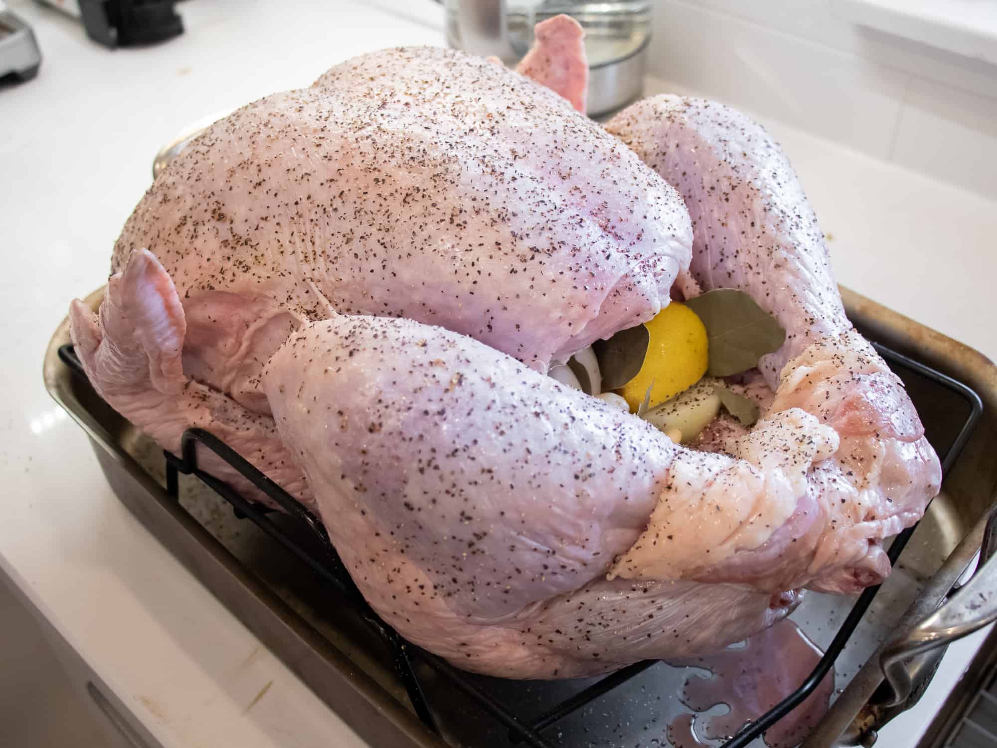 Season the raw chicken with salt and pepper. Fill cavity with onion, lemon and bay leaves