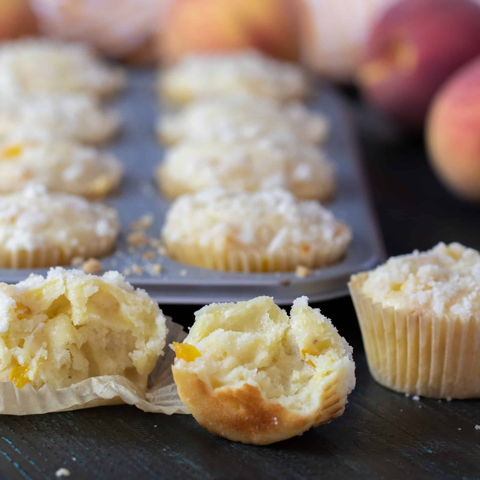 Fresh baked peach cobbler muffins and a buttery crumble topping.