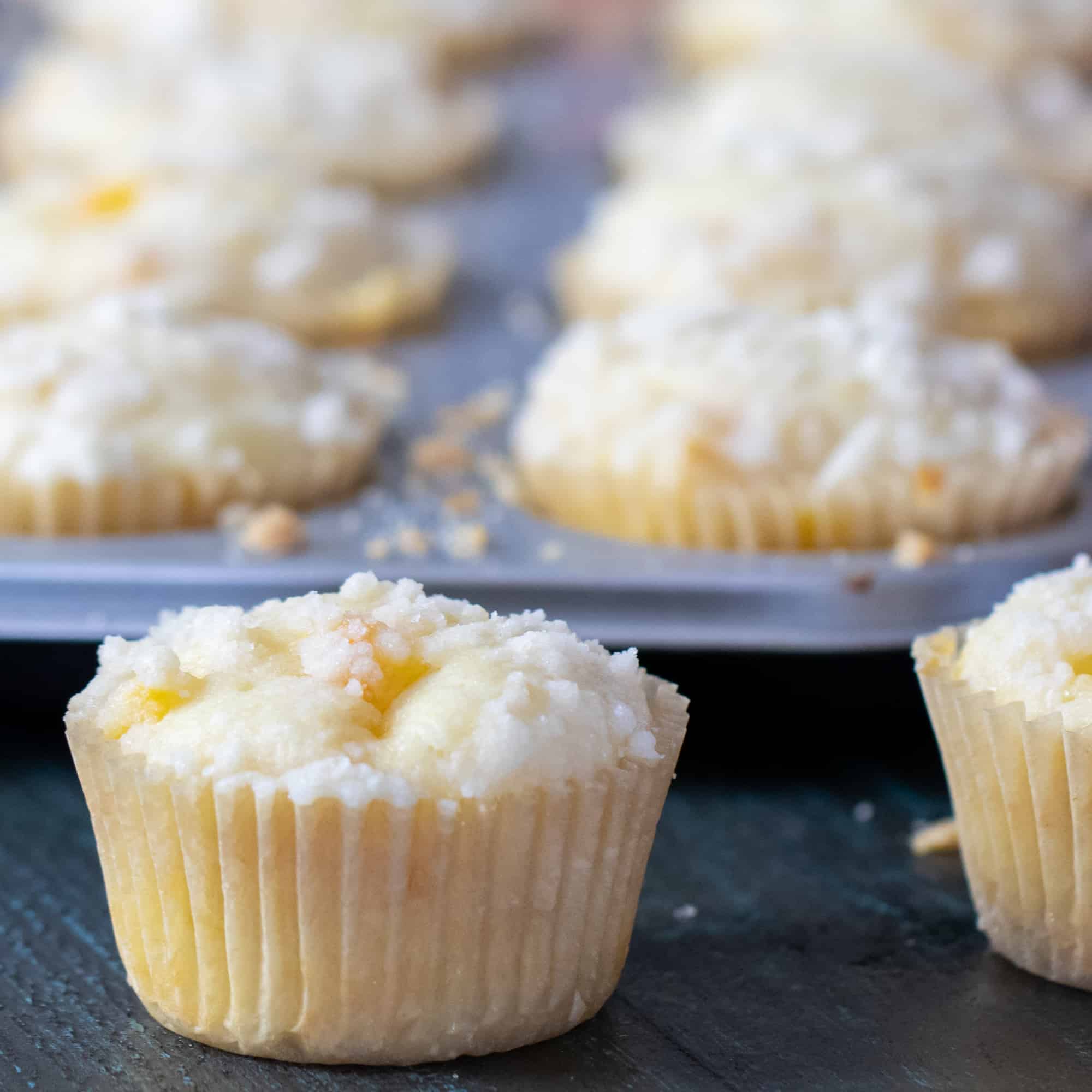 Fresh baked peach cobbler muffins and a buttery crumble topping.