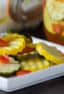 Quick recipe for small batch refrigerator zucchini pickles. Made with both green and yellow zucchini squash, red peppers, garlic, dill, and mustard seeds.