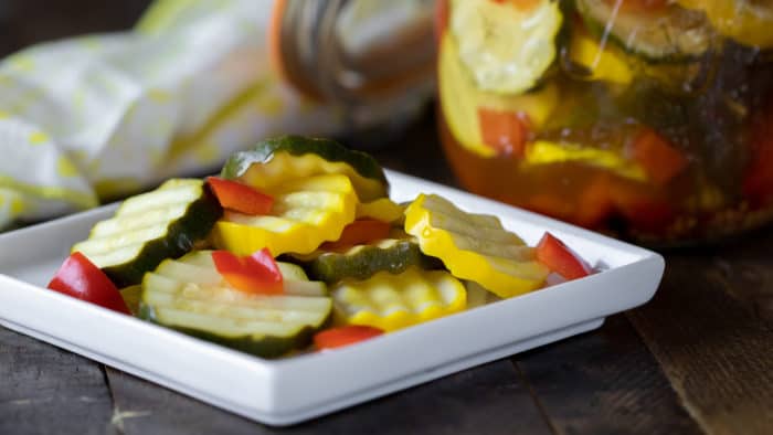 Quick recipe for small batch refrigerator zucchini pickles. Made with both green and yellow zucchini squash, red peppers, garlic, dill, and mustard seeds.