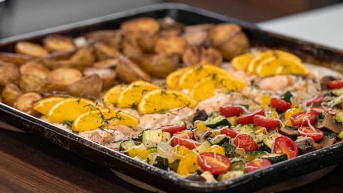 Easy recipe to make a one pan meal with frozen salmon fillets, mini potatoes and mixed vegetables. Delicious weeknight sheet pan dinner!