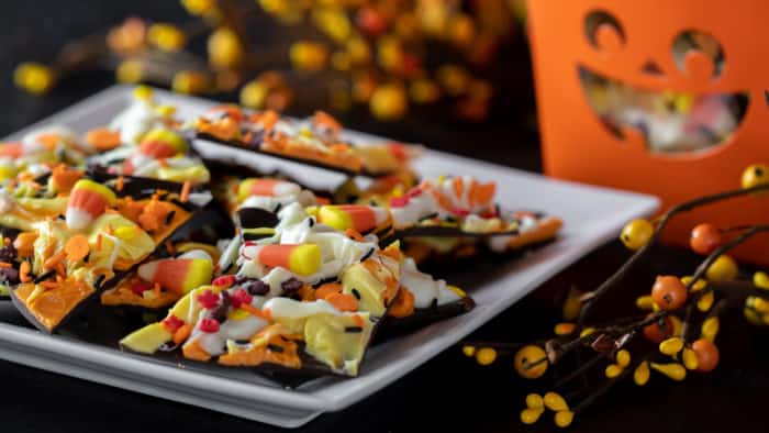 Chocolate bark recipe with a holiday Halloween theme. Sweet dessert treat made with dark chocolate melts, coloured candy melts, candy corn and sprinkles.