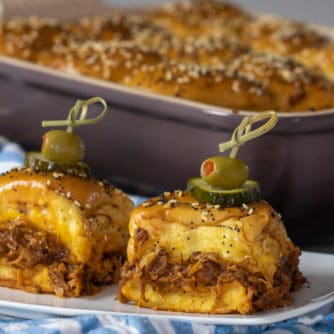 Two sliders on a plate in front of a baking dish.