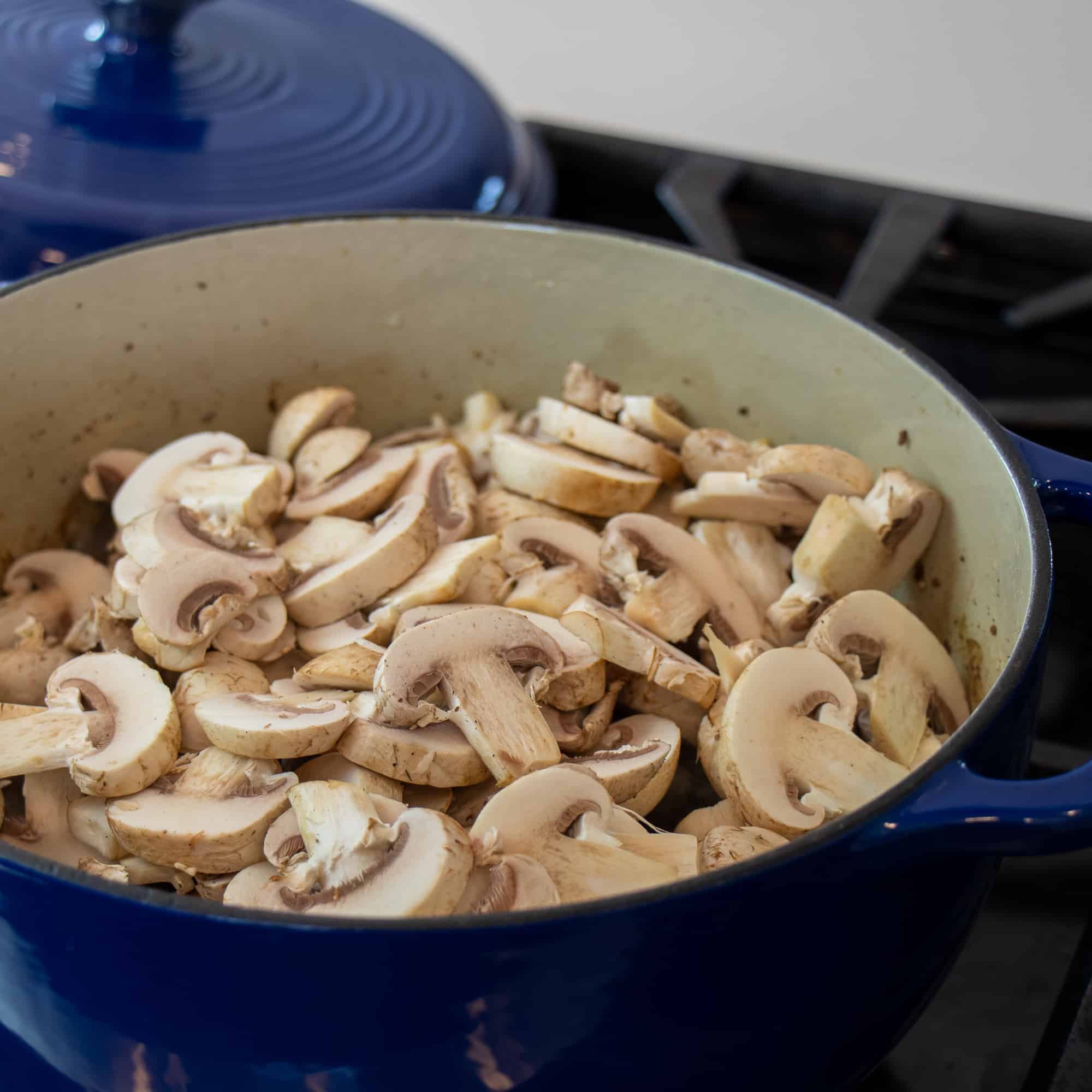 Sliced button mushrooms added to the dutch oven.