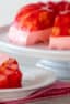 A Jello mold ring with fruit salad on a cake stand with a slice on a plate.