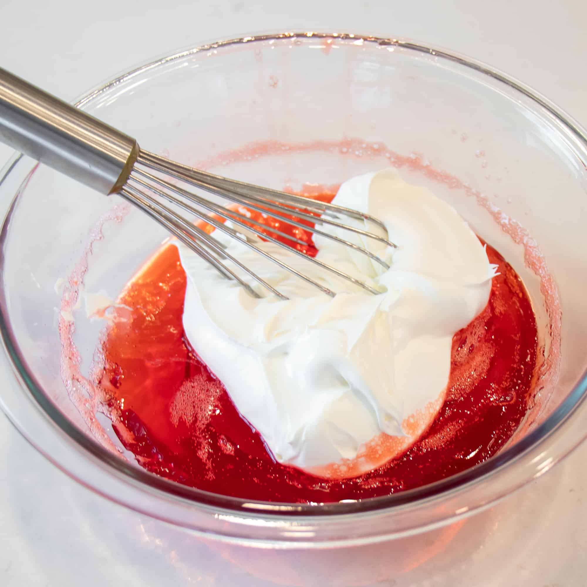 A bowl with the remaining Jello being whisked with the whipped cream.