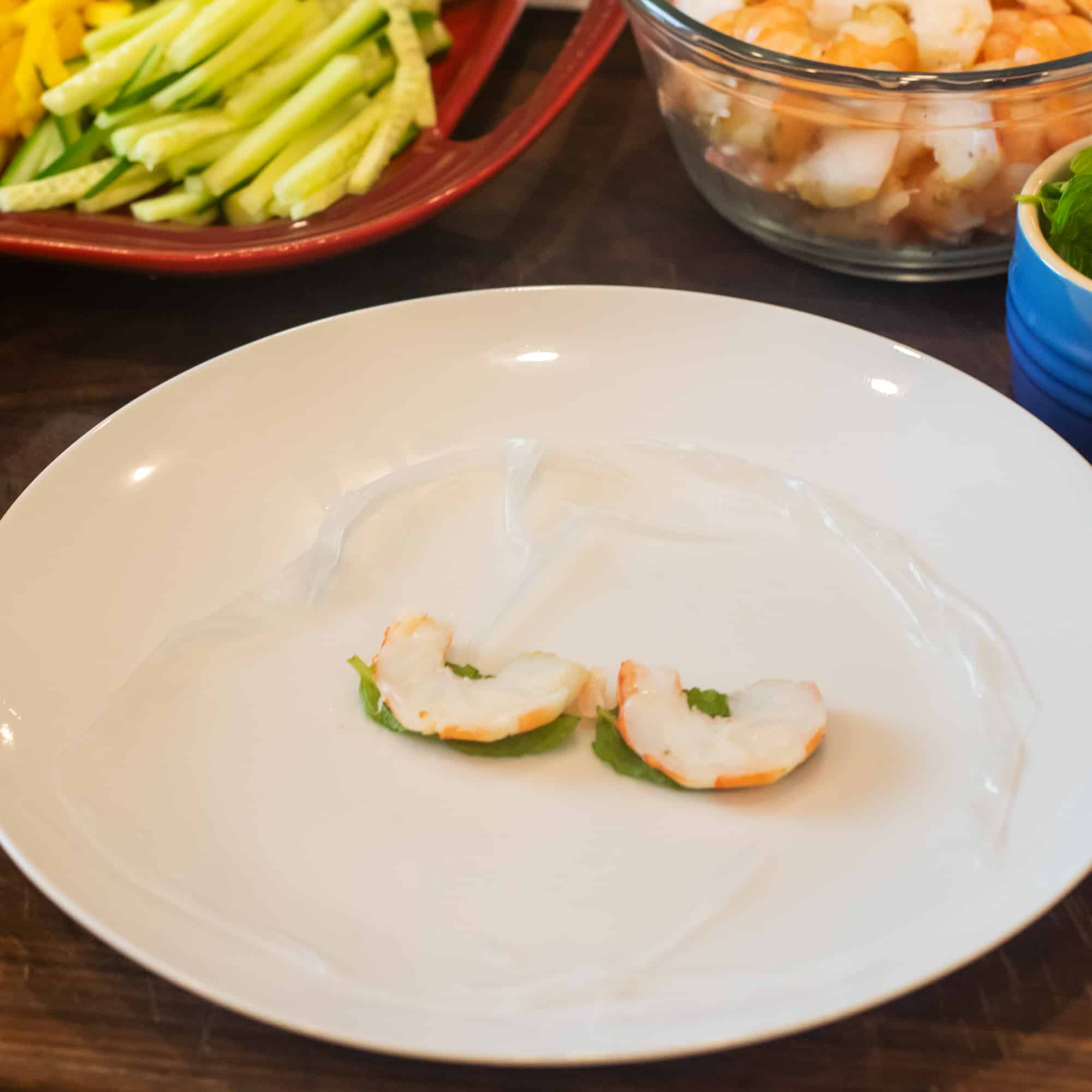 Place softened rice paper on a plate and place some fresh mint and shrimp in the centre.