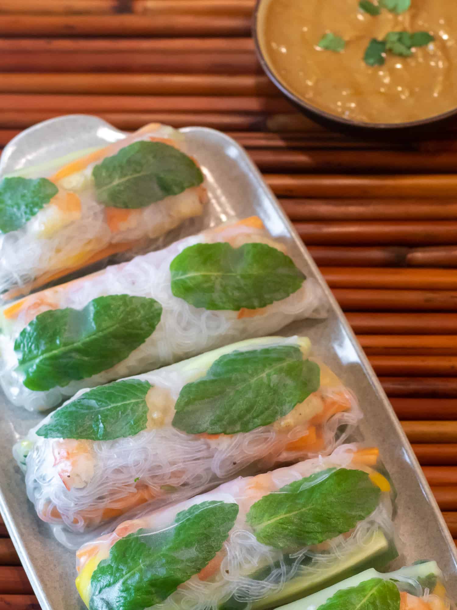 Overhead picture of plate of Vietnamese cold spring rolls with bowl of peanut sauce