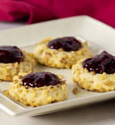 Classic recipe for thumbprint cookies rolled in chopped walnuts with a dollop of raspberry jam on top. Easy recipe and perfect for Christmas holiday baking.