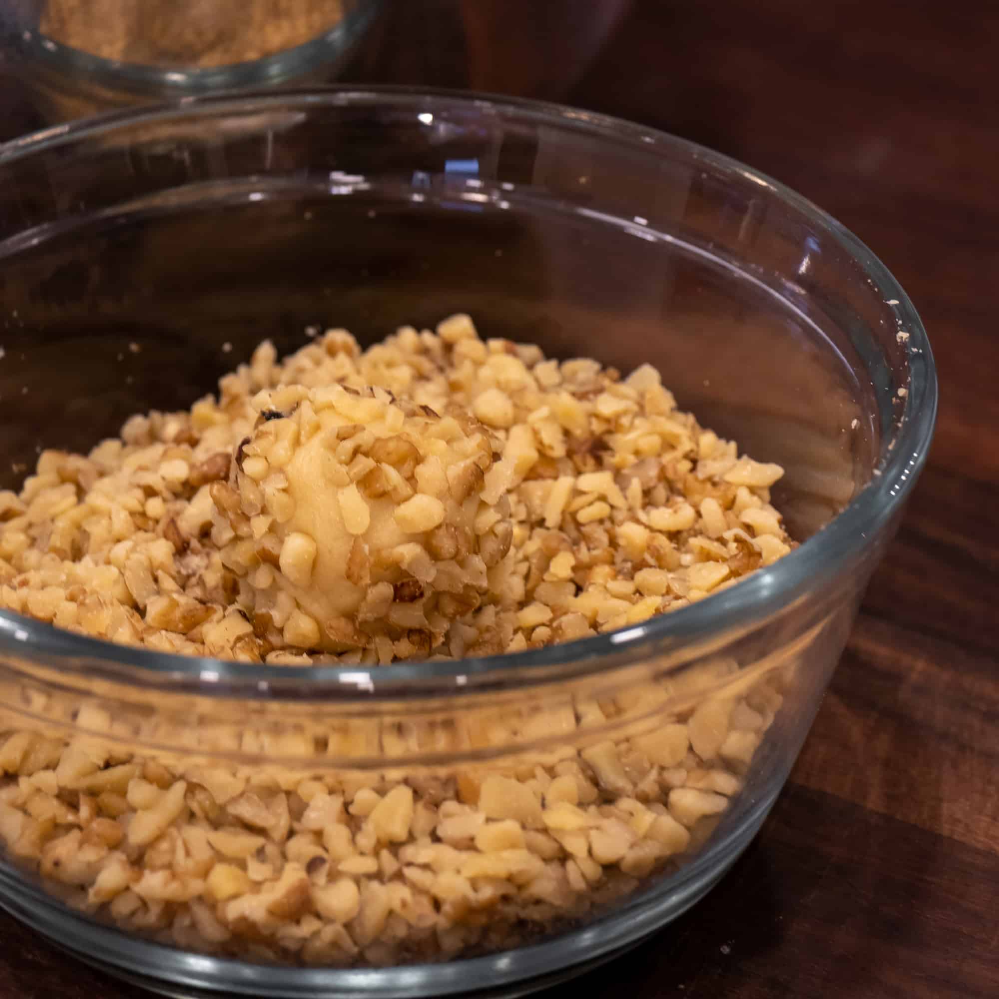 Roll the ball of dough in a bowl of chopped walnuts.