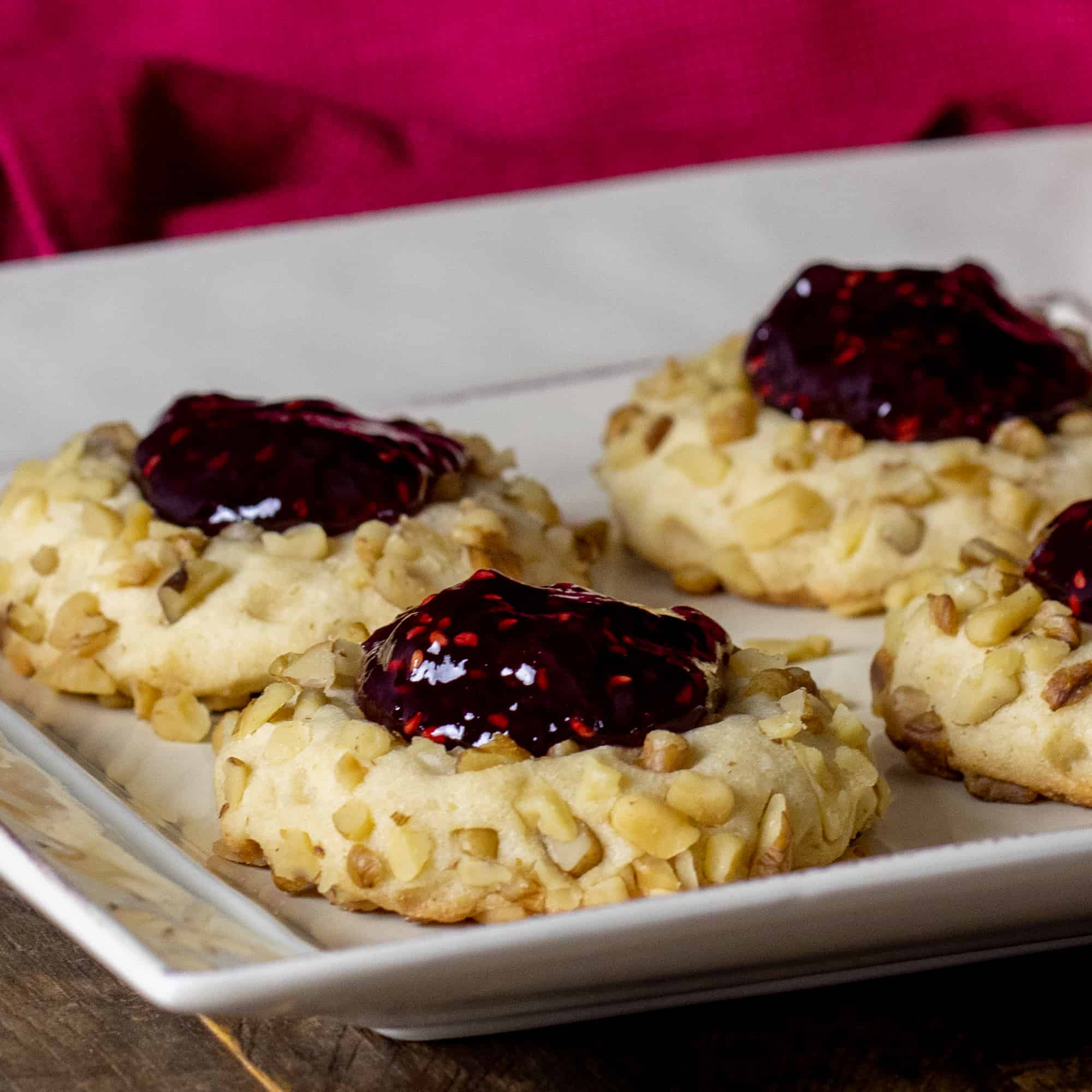 Four raspberry thumbprint cookies on a plate