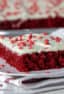 A slice of red velvet sheet cake on a plate with heart sprinkles.