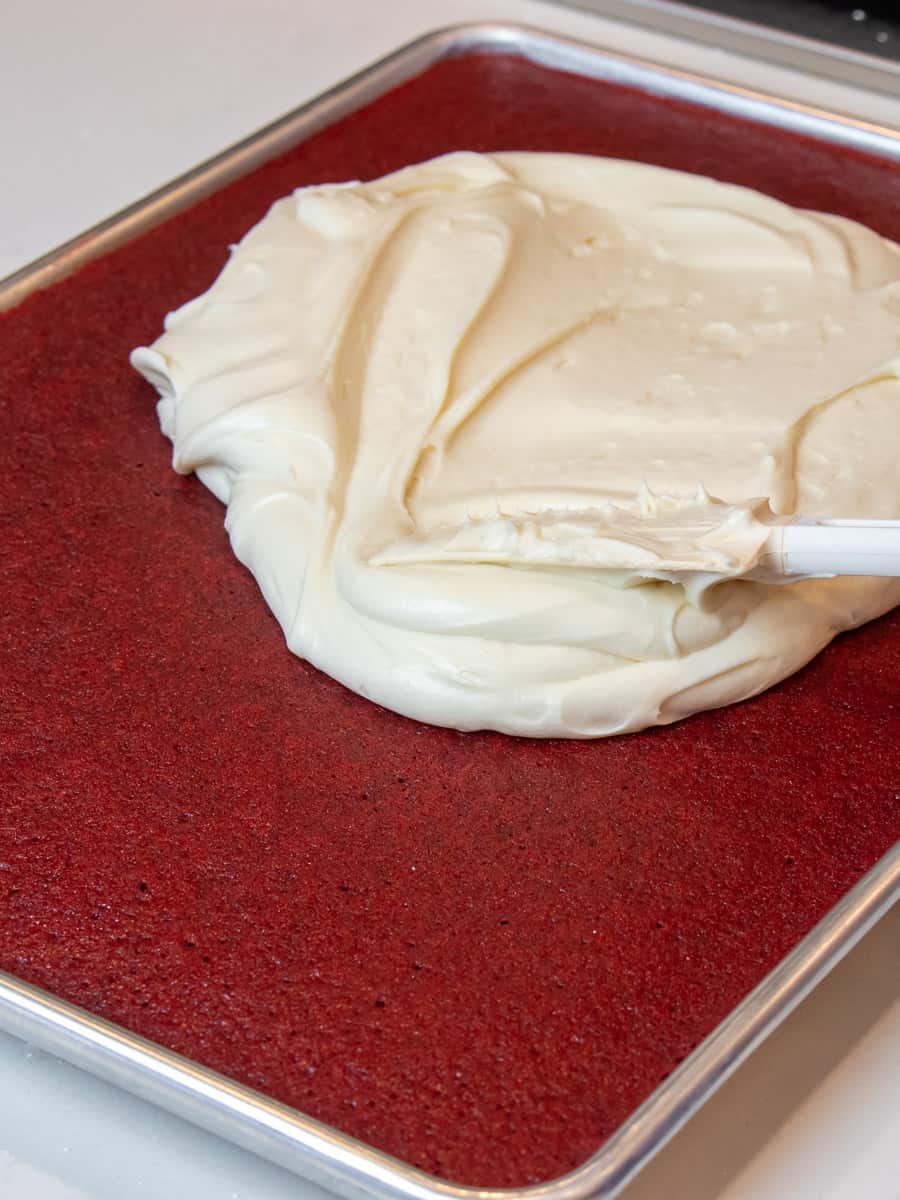 Spreading cream cheese frosting on cooled cake.