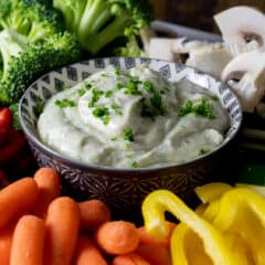 Creamy vegetable dip with raw carrots, peppers, cucumber, broccoli, and mushrooms.