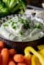 Creamy vegetable dip with raw carrots, peppers, cucumber, broccoli, and mushrooms.