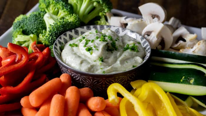 Creamy vegetable dip with raw carrots, peppers, cucumber, broccoli, and mushrooms.