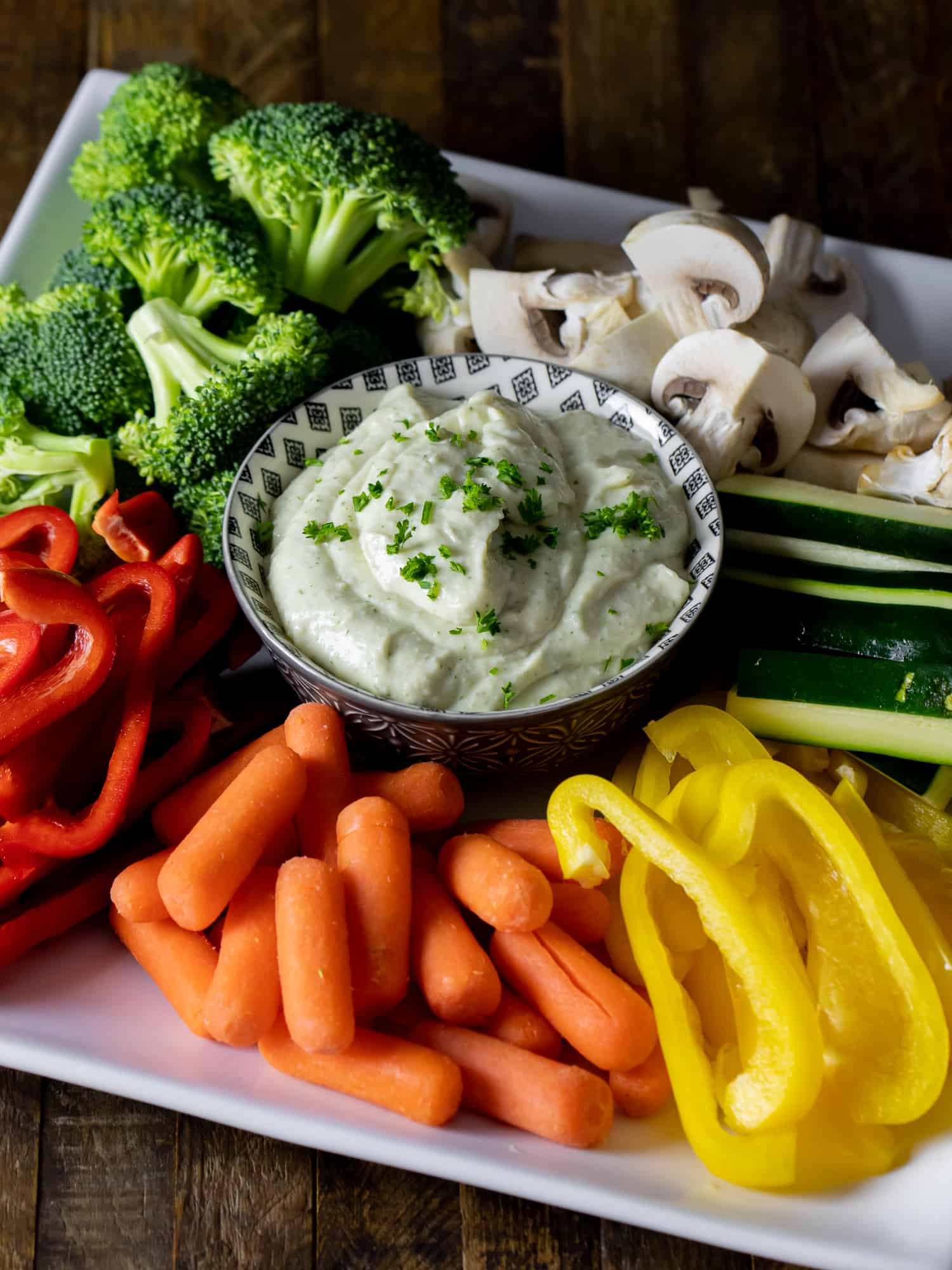 Creamy vegetable dip with raw carrots, peppers, cucumber, broccoli, and mushrooms.