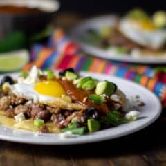 A plate with a Mexican corn tortilla, chorizo, pinto beans and eggs.