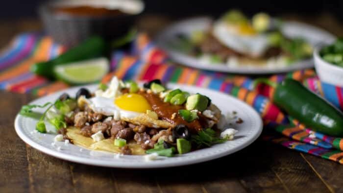 A plate with a Mexican corn tortilla, chorizo, pinto beans and eggs.