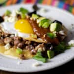 A plate with a Mexican corn tortilla, chorizo, pinto beans and eggs.