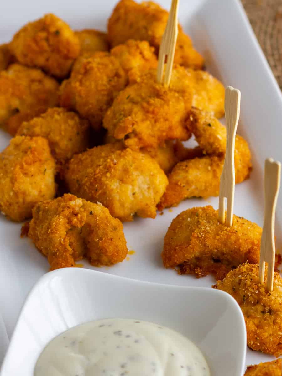 Tall image of a plate of nuggets with dip.