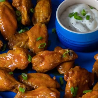 A platter of wings and ranch sauce for dipping.